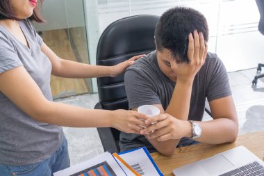 Ofisteki kadın yorgun ortağına su getiriyor.