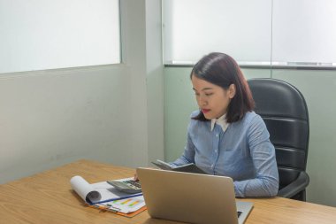 Genç işletme çalışanı hesap makinesiyle mali raporlar üzerinde çalışıyor