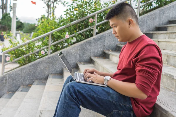 Oldalnézet fiatal ázsiai férfi dolgozik laptop — Stock Fotó
