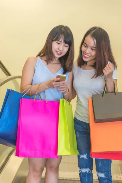 Young girls holding shopping bag and checking online deal — 스톡 사진