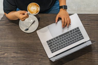 İnsan elinin kahve dükkanında dizüstü bilgisayar kullanırken en üstteki fotoğrafı.