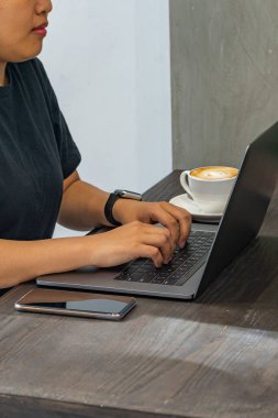 Kahve dükkanında dizüstü bilgisayarı daktilo eden kadınların yakın çekim fotoğrafı.