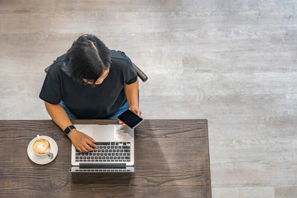 Mujer asiática freelancer usando smartphone y laptop en café co-working — Foto de Stock