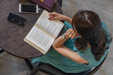 Kahve masasında kitap okuyan bir kadının en iyi görüntüsü.
