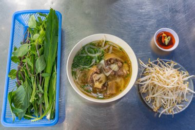 Bowl of Vietnamese Pho beef noodle served with vegetables