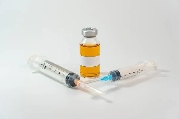Orangefarbene Impfflasche mit leerem Etikett und Spritze auf weißem Hintergrund — Stockfoto