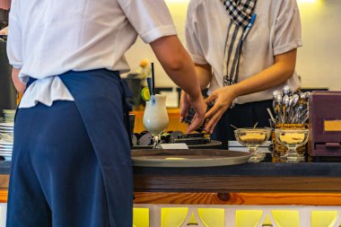 Garson kahve tezgahındaki tepside içki topluyor. 