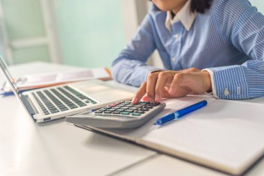 Ofisteki toplantı odasında hesap makinesi kullanan genç Asyalı iş kadını.