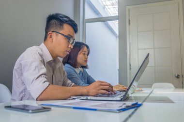 Ofiste dizüstü bilgisayarla çalışan Asyalı iş adamları.