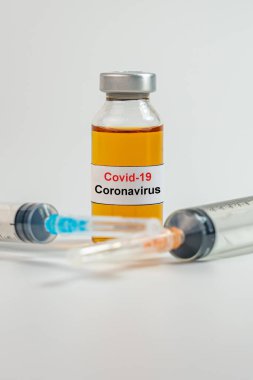 Coronavirus aşı şişesi ve şırınga iğnesinin dikey fotoğrafı