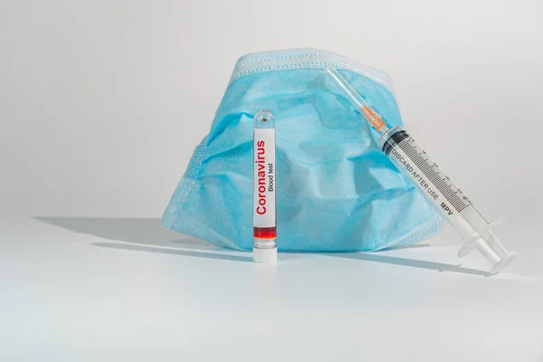 Bloedmonster voor coronavirustest met injectiespuit en chirurgisch masker — Stockfoto