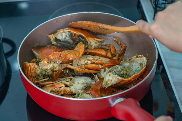 Mano umana con spatola e cottura di granchio fritto — Foto Stock