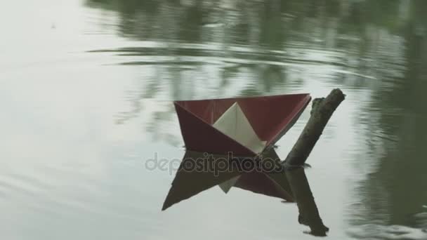 A paper boat in the river bends around the stick — Stock Video