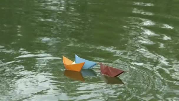 Três barcos de papel multicoloridos flutuando no rio . — Vídeo de Stock