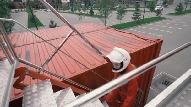 Chica en mono rojo y casco protector se eleva escaleras arriba — Vídeo de stock