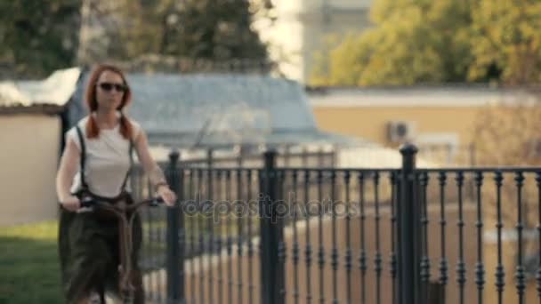 Red haired woman riding a bicycle — Stock Video