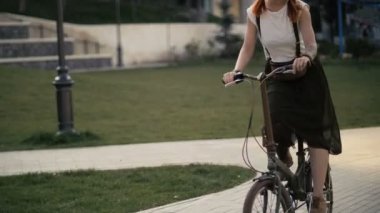 Seksi redhaired kadın yaz parkta Bisiklete binmek kapatın. Kadın bisiklet sürme