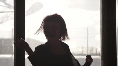 Bir pencere önünde dans bir kız silüeti