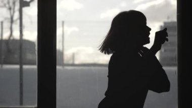 Bir pencere önünde dans bir kız silüeti