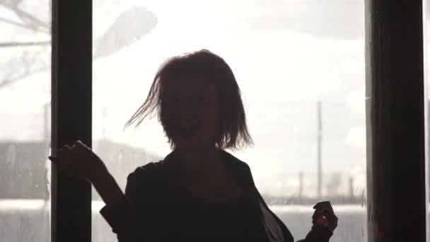 Силуэт девушки, танцующей перед окном — стоковое видео