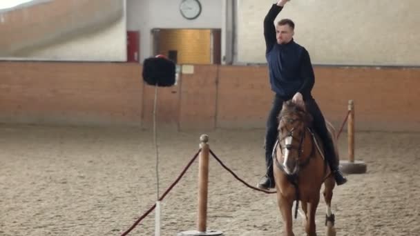 Jovem montando seu cavalo e balançando sua espada. Um cavaleiro cossaco corta um chapéu cossaco . — Vídeo de Stock