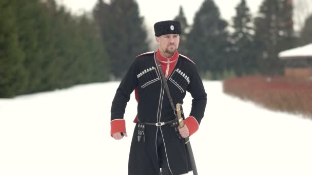 Cosaco con dagas caminando por el paisaje invernal. Un joven camina por la nieve . — Vídeos de Stock