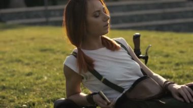 Redhaired kadın bisikletçi yaz Park yeşil çim üzerinde dinlenme