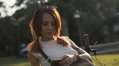 Bisiklet kadın yaz Park cep telefonunda mesaj yazarak