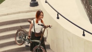 Merdivenlerden aşağı yürüme ve bisiklet kollarında tutan kadın bisikletçi. Kadın Bisiklet şehir