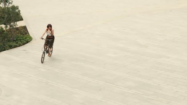 Žena cyklista na kole na zpevněné silnici na náměstí na letní den