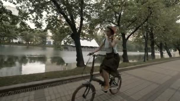 Femme rousse chevauchant un vélo sur le lac de fond de la ville. Femme vélo ville — Video
