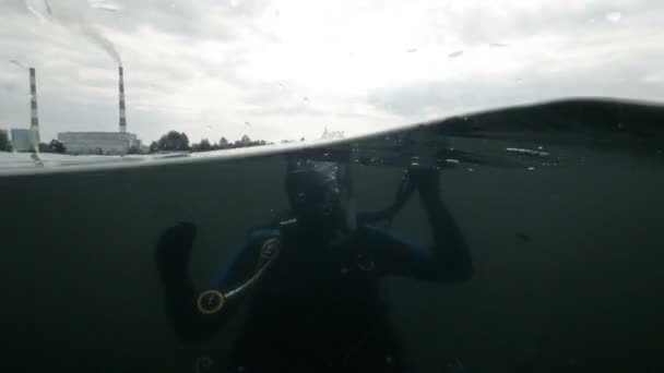 Diver nedsänkt i flodvatten på bakgrunden rökning skorstenen kemisk fabrik — Stockvideo