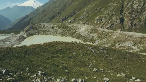 Senderismo personas en el fondo lago de montaña y picos de montaña — Vídeos de Stock