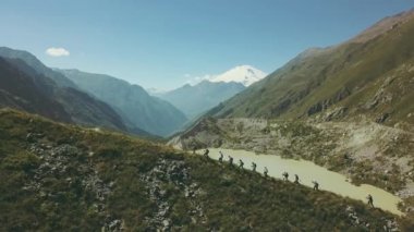Panoramik dağ manzaralı göl ve kar tepe üzerinde yürüyen insanlar hiking