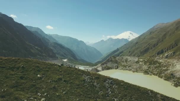 Панорамний вид туристичної групи, що стоїть на горі на фоні гірського озера — стокове відео