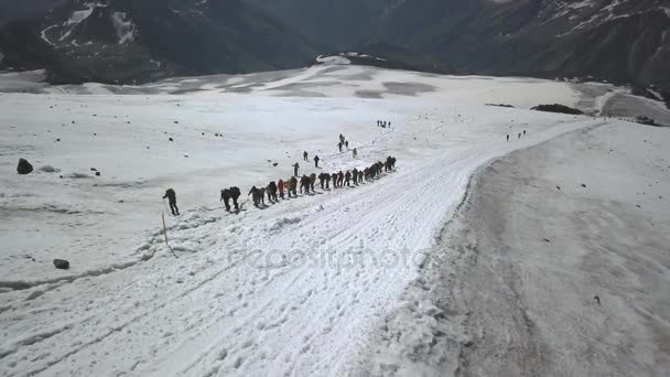 Drone ver a los turistas en crampones y palos de seguimiento en la montaña en el sendero de nieve — Vídeos de Stock