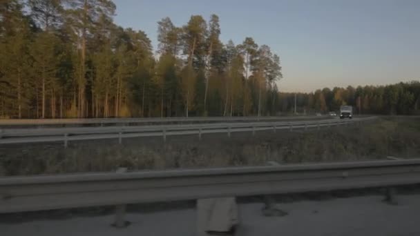 Camión de carga y coche de conducción en la carretera suburbana en el paisaje de otoño de fondo — Vídeos de Stock
