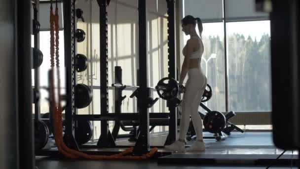 Wanita fit membuat kecenderungan dengan barbel untuk melatih otot bokong di klub — Stok Video