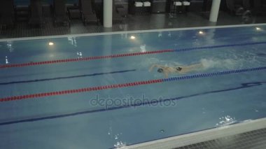 Kadın profesyonel yüzücü gezinme kontur su lüks yüzme havuzunda yüzen