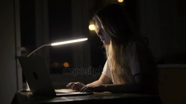 Karanlık odada online eğitim için dizüstü bilgisayar kullanan kadın öğrenci