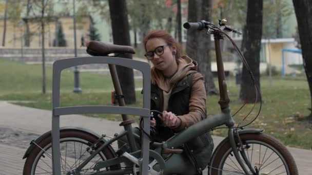 Radfahrerin benutzt Schlüssel zum Verschließen von Schloss auf Fahrradabstellplatz im Stadtpark — Stockvideo