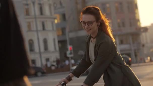 Stående ung kvinna rider en cykel i kväll city och tittar in i kameran — Stockvideo
