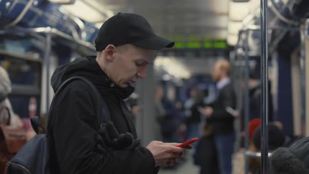 Hombre guapo mirando en el teléfono inteligente de la pantalla y el uso de la aplicación móvil en tren metro — Vídeo de stock