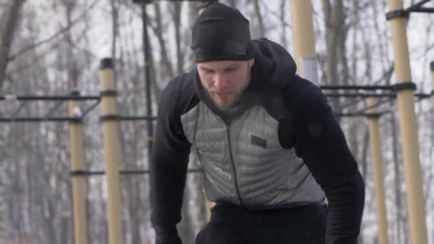 Strong man training with fitness expander on winter sport ground on frosty day — Stock Video