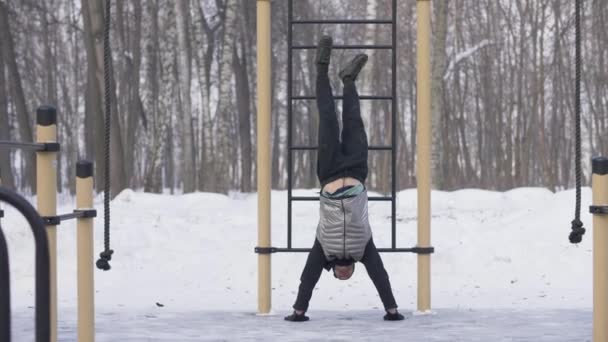 Man training push ups exercise with legs raising up on winter sport ground — Stock Video