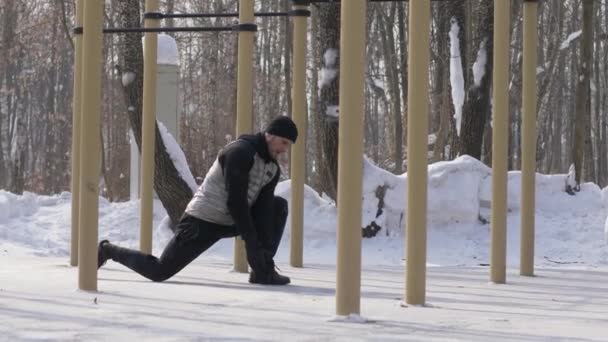 Hombre de deporte haciendo ejercicio en el campo de deportes de invierno. Entrenamiento de fitness — Vídeos de Stock