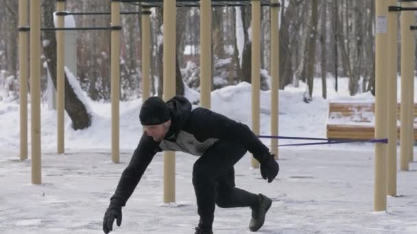 Hombre fuerte haciendo ejercicio con expansor en el entrenamiento al aire libre — Vídeos de Stock
