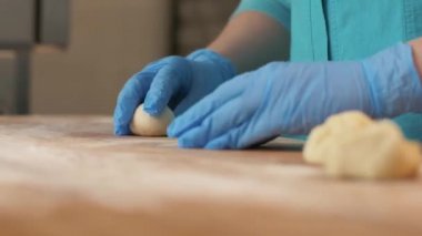 Baker el fırın dükkanda ahşap masa topları hamur köftesi için yapma