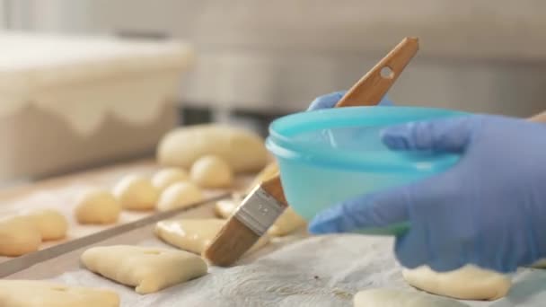 Baker mano infligge miscela di uova con pennello sulle polpette prima di cuocere sul tavolo — Video Stock