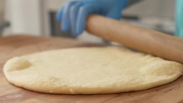 Hand pizza maker rolling dough on table for baking in restaurant close up